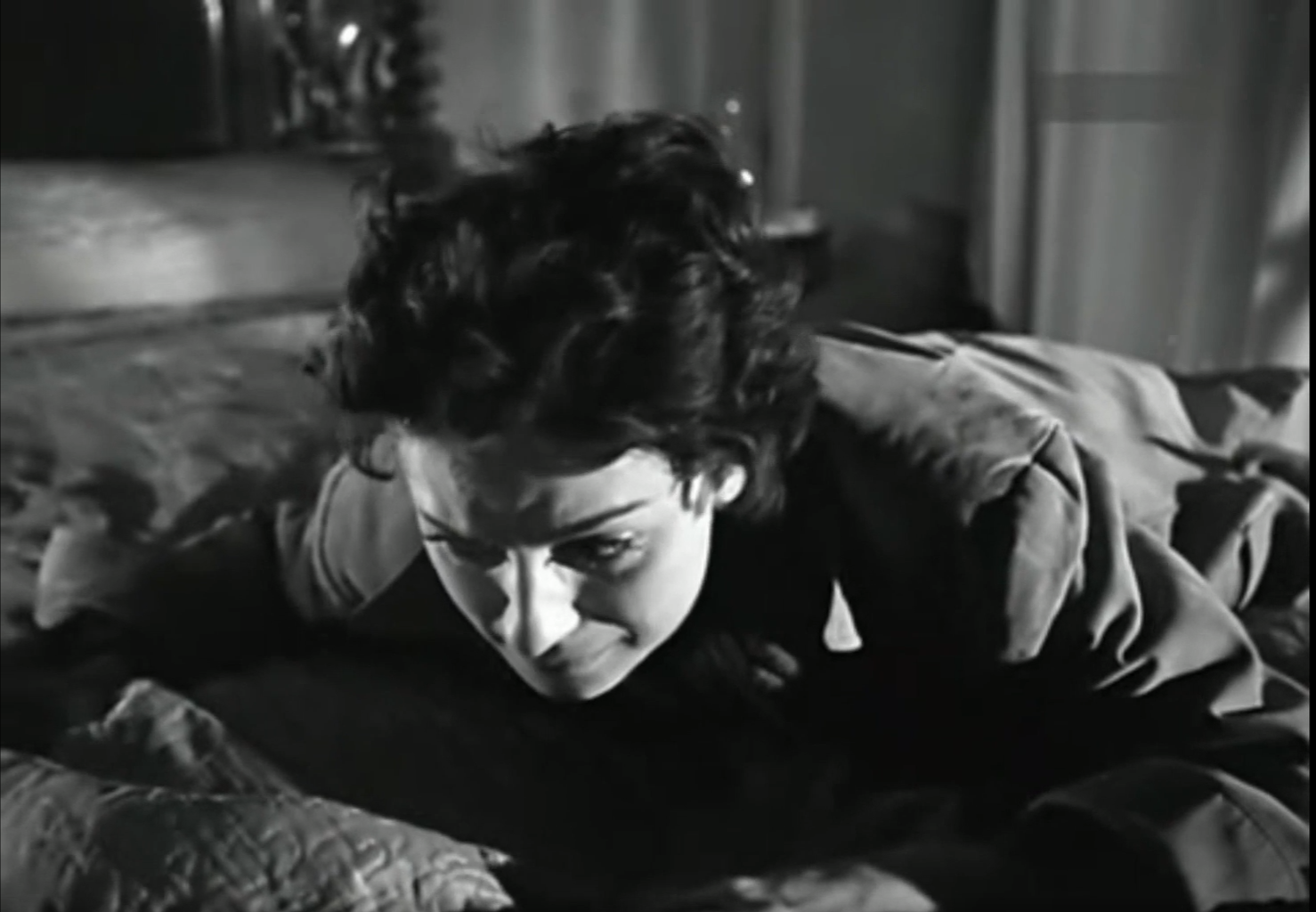 Una persona con expresión de tristeza o angustia está recostada boca abajo sobre una cama en una escena en blanco y negro.

Description generated by AI