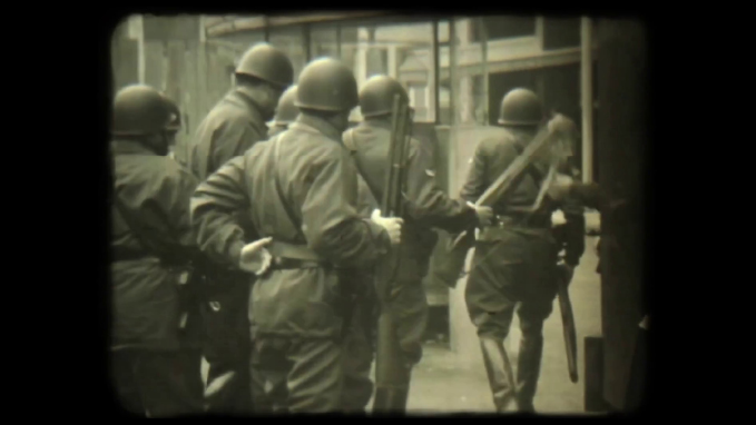 Un grupo de personas con uniformes militares y cascos están caminando por una calle en un entorno urbano con un estilo visual antiguo en blanco y negro.

Description generated by AI