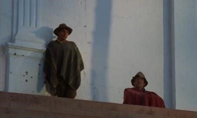 Dos personas con sombreros y ponchos están sobre una estructura de piedra frente a una pared blanca.

Description generated by AI